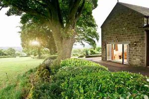 Lush green garden and open white aluminium Aluminium Door on a heritage brick house in Bristol