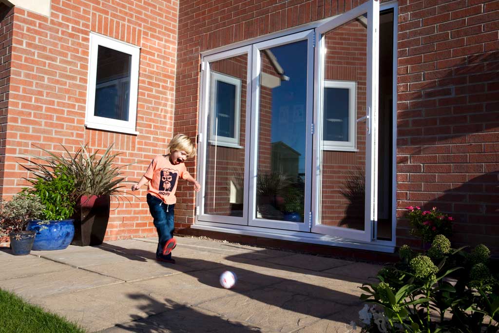 uPVC bifold doors on a red brick house with a child playing on the patio