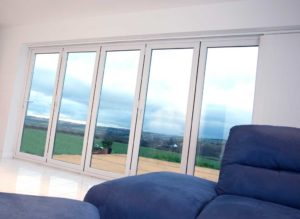 White uPVC bifold doors in a white room next to a blue sofa