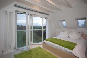 Open white uPVC bifold doors in a white and green bedroom