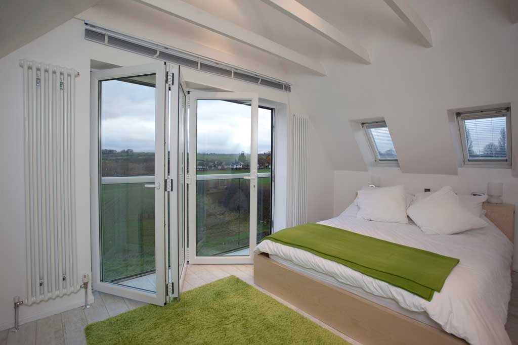 Open white uPVC bifold doors in a white and green bedroom 