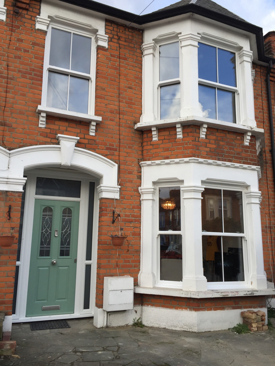 brown brick building with a green door and bow and bay sliding sash windows in bristol
