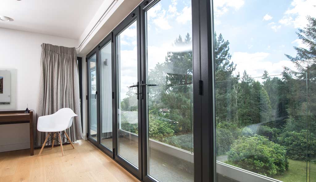 aluminium bifold doors in a bedroom with lush green view in Bristol