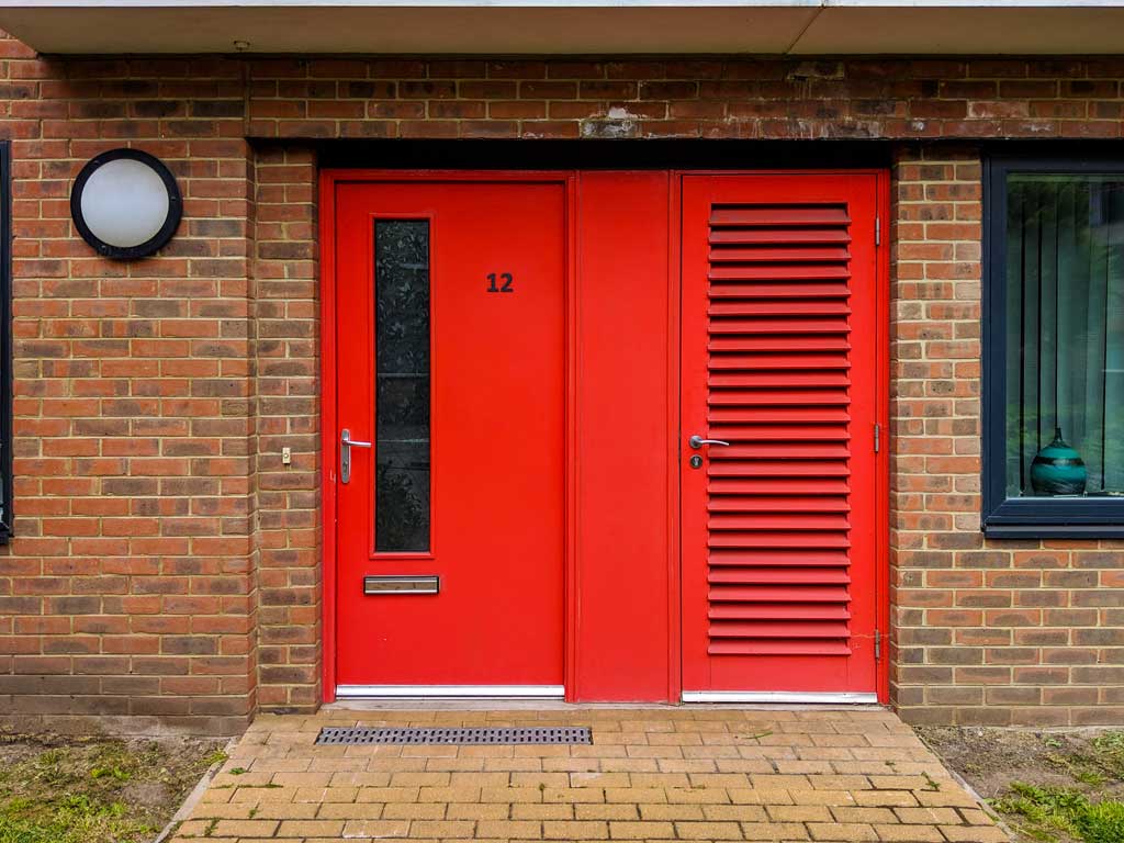 red composite entrance doors on a brown brick building Bristol