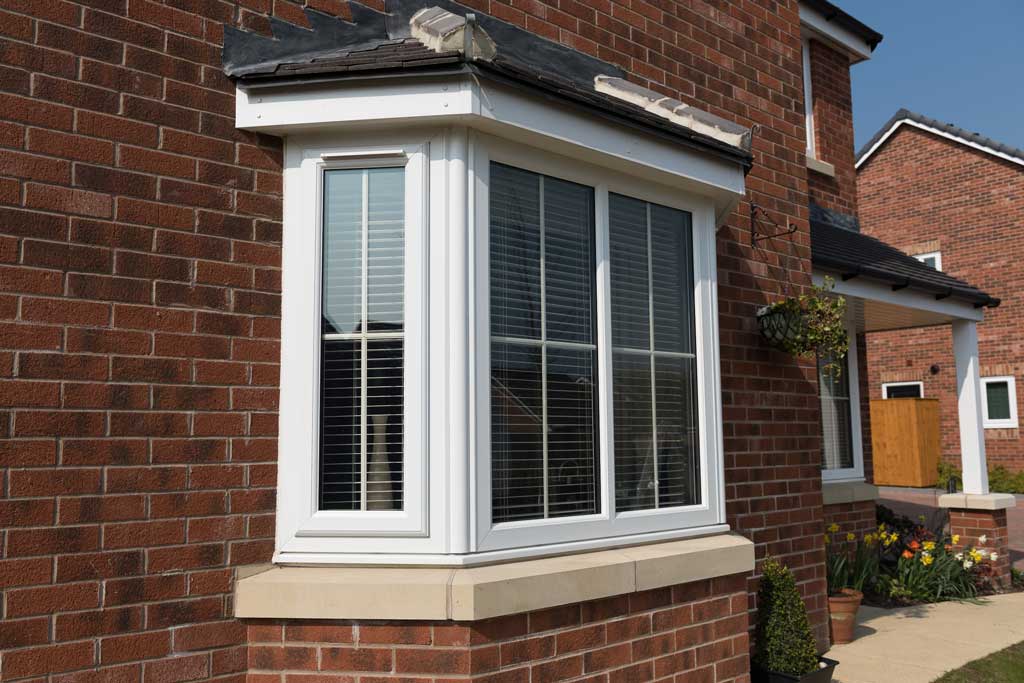 Triple glazed white uPVC bay windows on a red brick wall